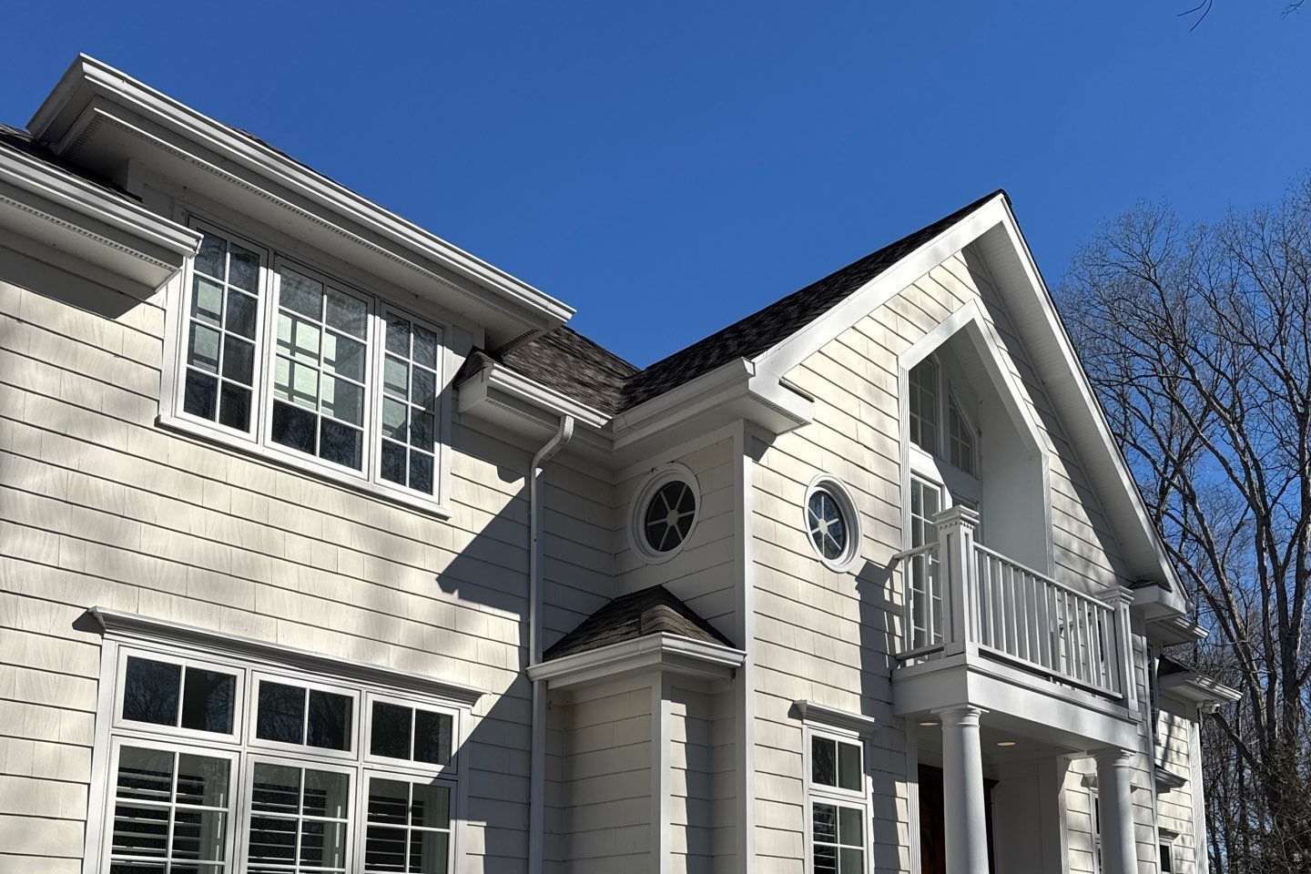 White shingle-sided colonial home under a clear blue sky in Fairfield County, CT