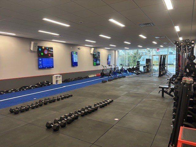 Fitness studio floor with rows of kettlebells and wall-mounted screens