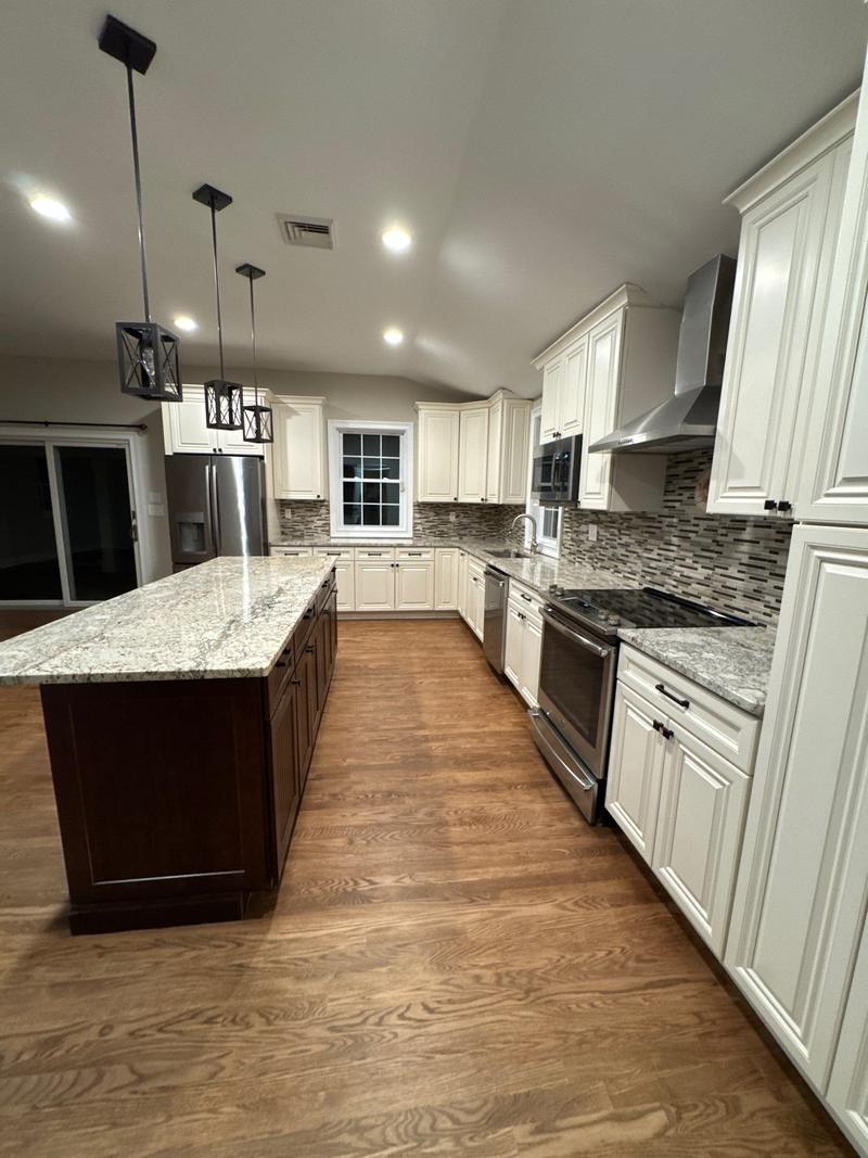 Empty kitchen with cream cabinets, a granite island and hardwood floors