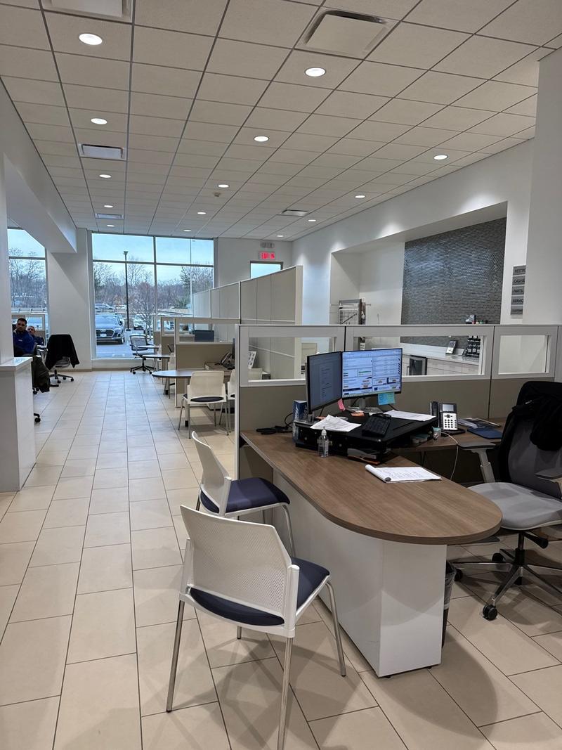 Open-plan office with a curved reception desk, cubicles and a tiled floor