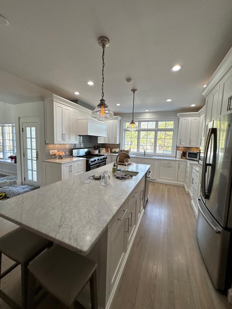Bright white kitchen with a marble-topped island, pendant lights and stainless appliances